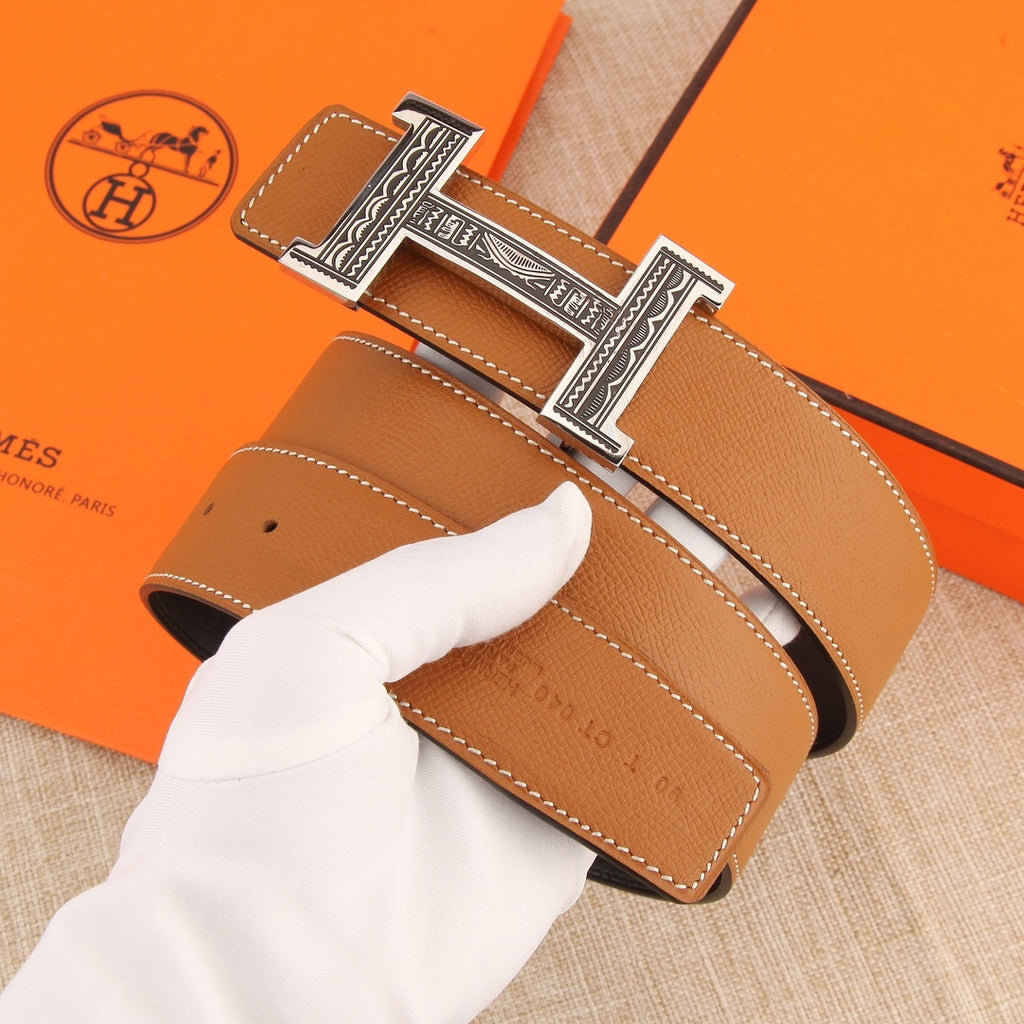 Hermes belt close-up: tan strap with stitched trim and silver-tone H buckle.