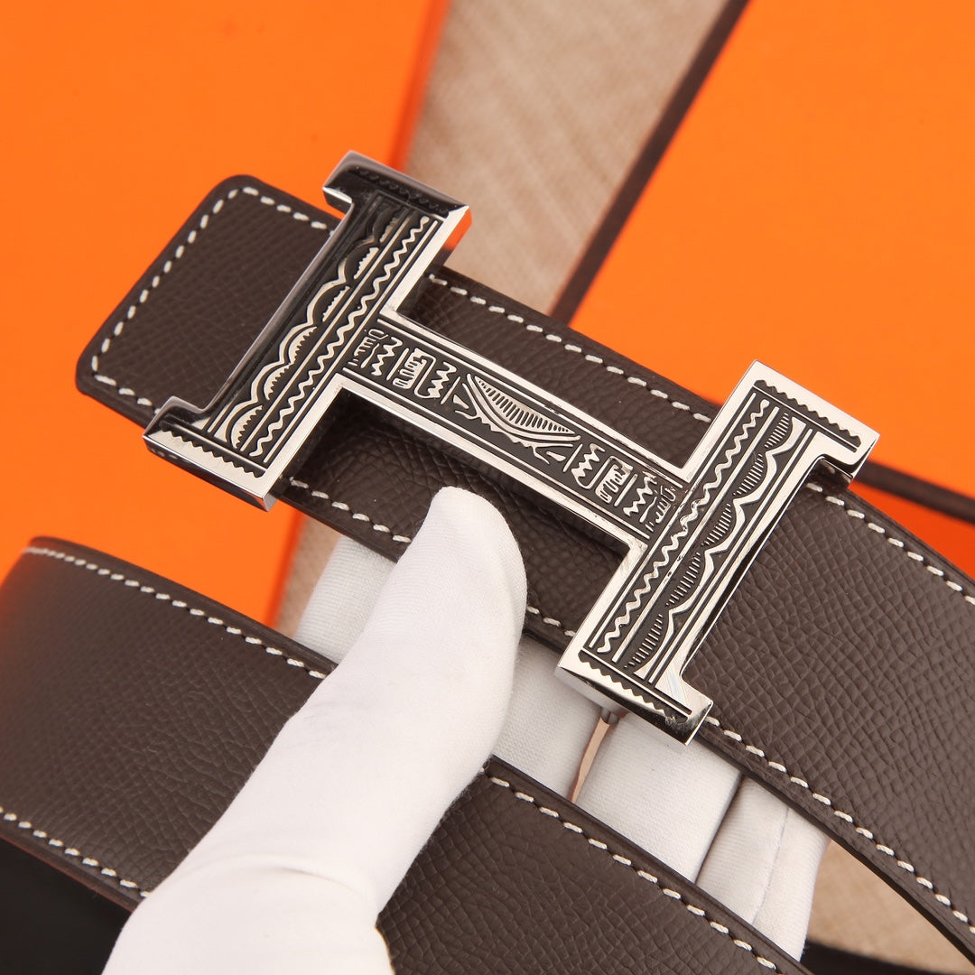 Brown leather belt buckle detail with engraved silver emblem and stitched edges