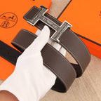 Brown leather belt close-up with ornate silver buckle and double-row stitching