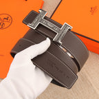 Brown leather belt with ornate silver buckle, perforated holes and stitched trim