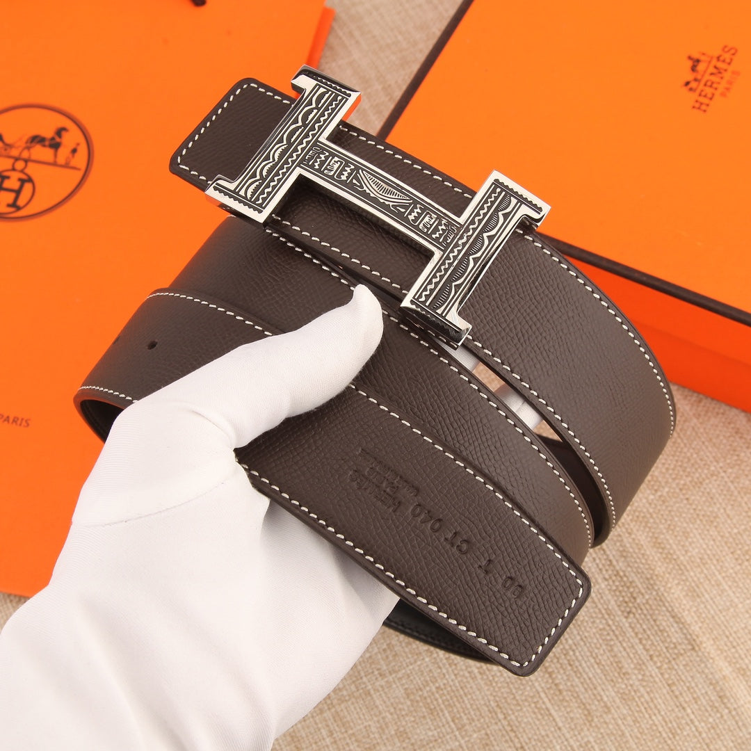 Brown leather belt with ornate silver buckle, perforated holes and stitched trim
