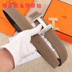 Hermes belt with dark brown leather strap and silver H buckle, shown with accessories