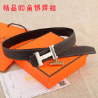 Brown leather belt with metal buckle and white stitching, laid over papers and box.