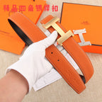 Hermes leather belt with orange strap, silver H buckle, and punched holes