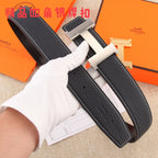 Black pebbled leather belt with gold-tone H buckle, held by white-gloved hand
