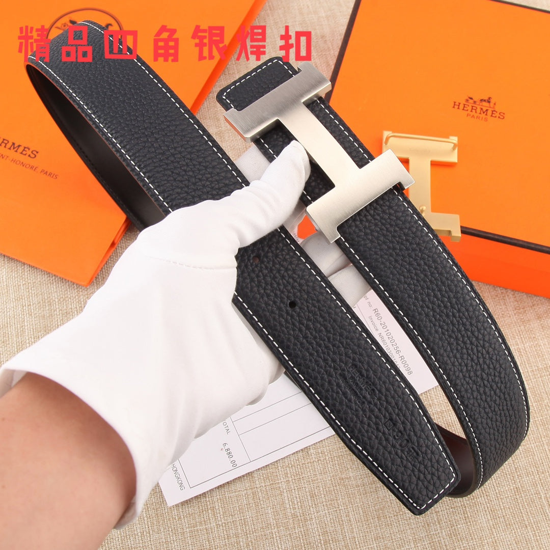 Black pebbled leather belt with gold-tone H buckle, held by white-gloved hand