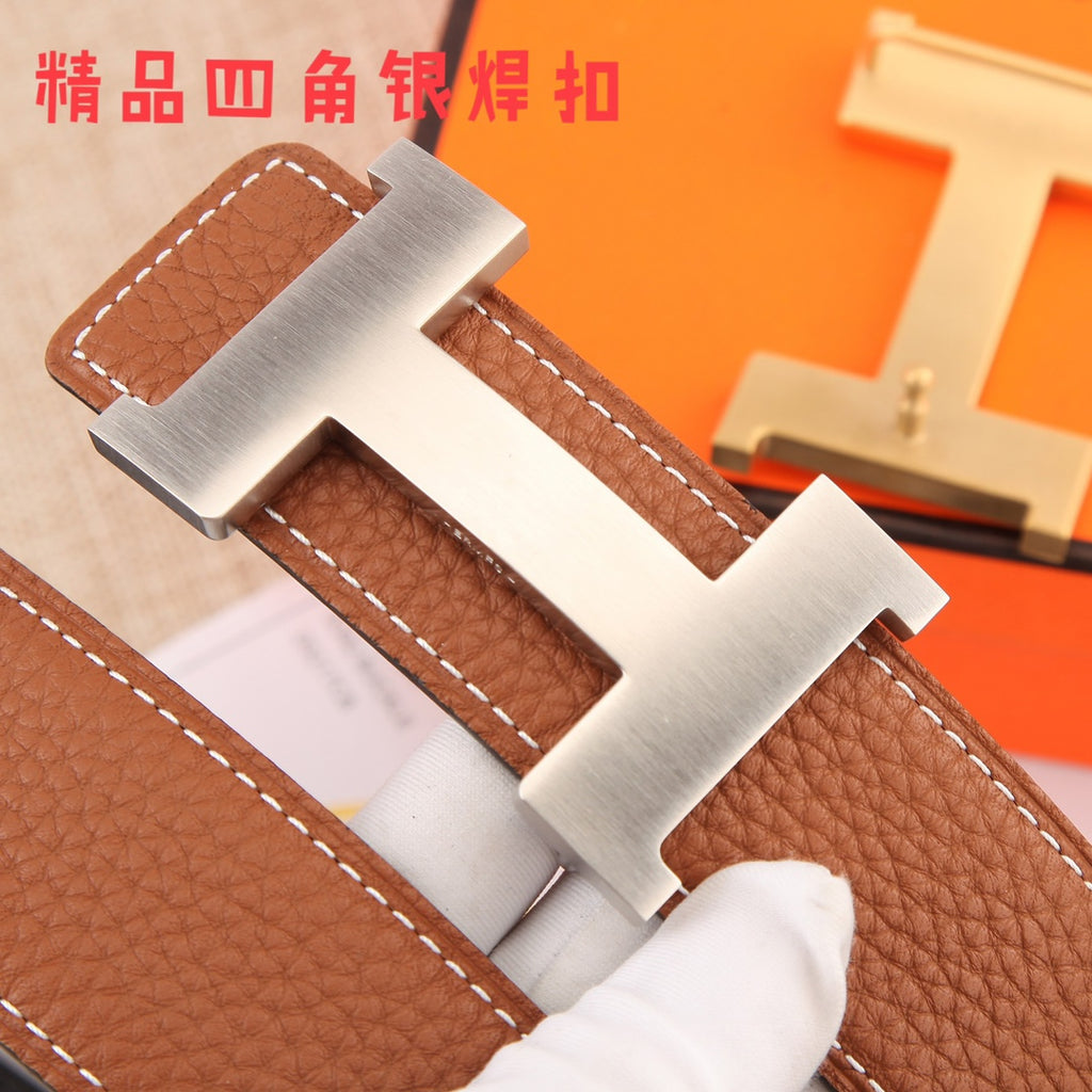 Hermes leather belt close-up of gold-tone H buckle on brown textured leather strap.