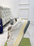 Gucci leather sneakers from front-side angle; white upper with beige sole and logo