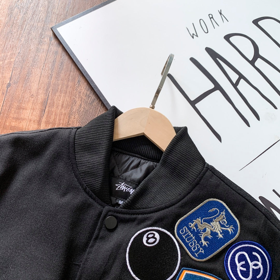 Black bomber jacket neckline close-up with ribbed collar and patches
