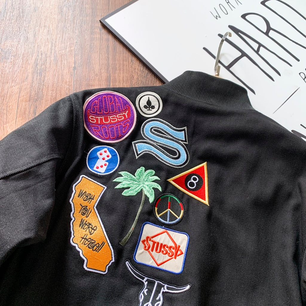 Black bomber jacket back close-up with colorful embroidered patches
