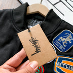 Black bomber jacket close-up with tag and embroidered crest patches