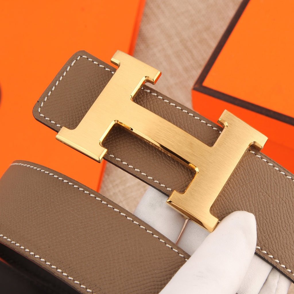 Hermes belt close-up of gold-tone H buckle on textured brown leather strap