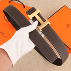 Dark leather belt with gold H buckle and adjustable strap holes, white stitching