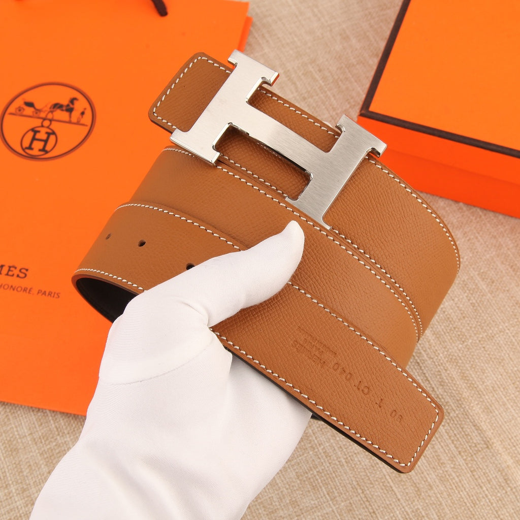 Hermès belt strap close-up with tan leather, silver buckle, and stitched keeper