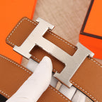 Hermès belt buckle detail, silver H-style hardware on tan leather with stitching