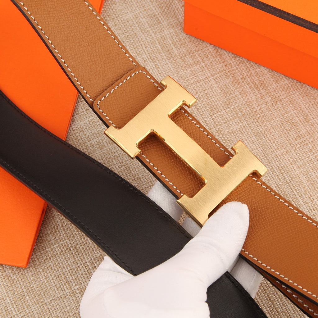 Hermès belt buckle close-up on tan leather strap with white-stitched edges
