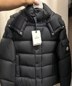 Long puffer jacket in dark color with hood, front buttons, and hanging brand tag