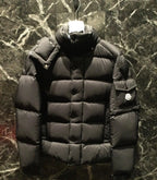 Long puffer jacket in dark color with hood, thick quilted insulation and side logo patch