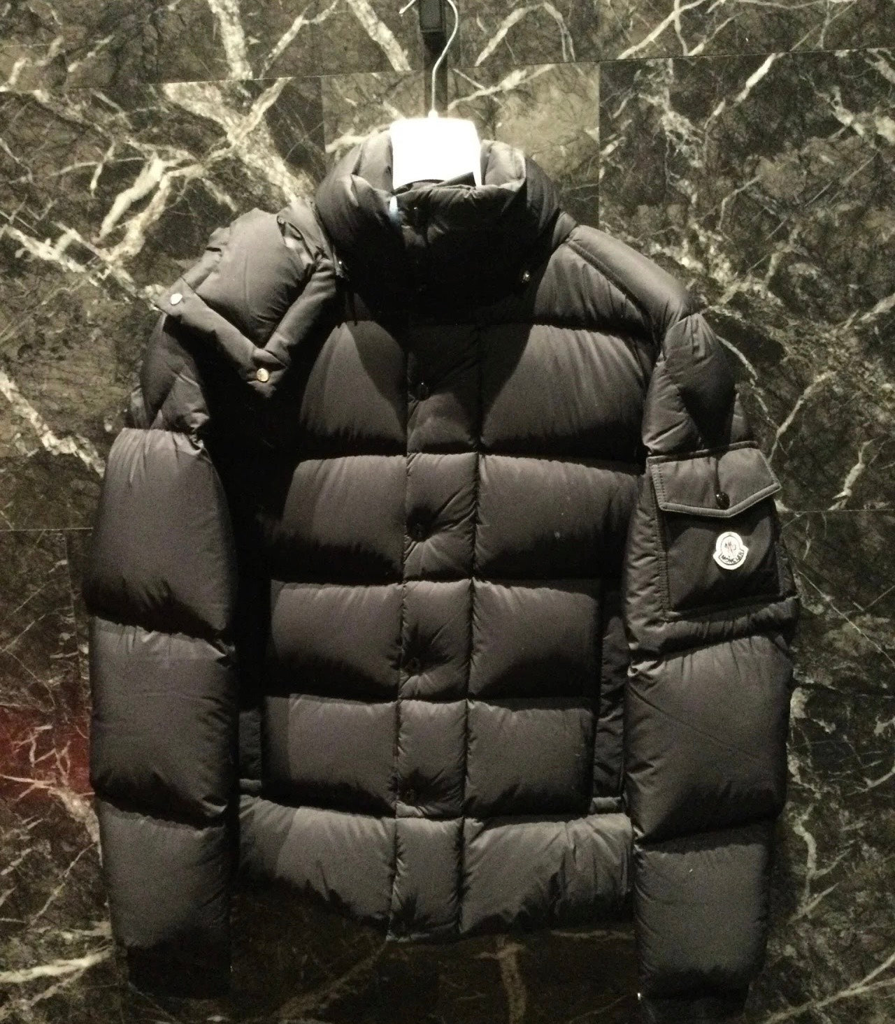 Long puffer jacket in dark color with hood, thick quilted insulation and side logo patch