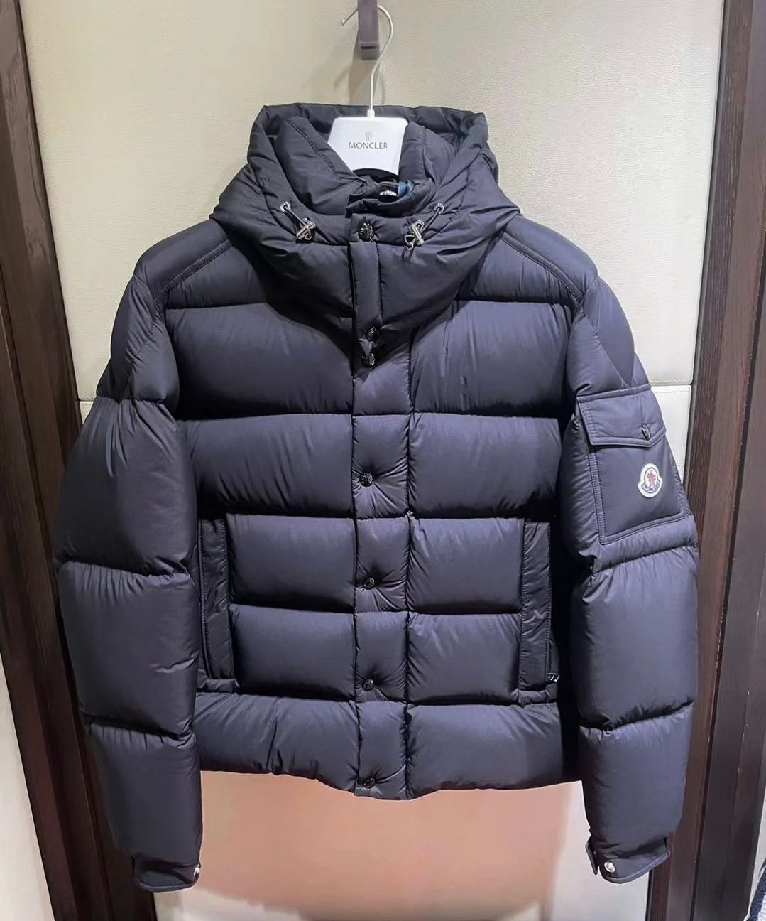 Long puffer jacket in dark color, hooded collar and quilted front panel