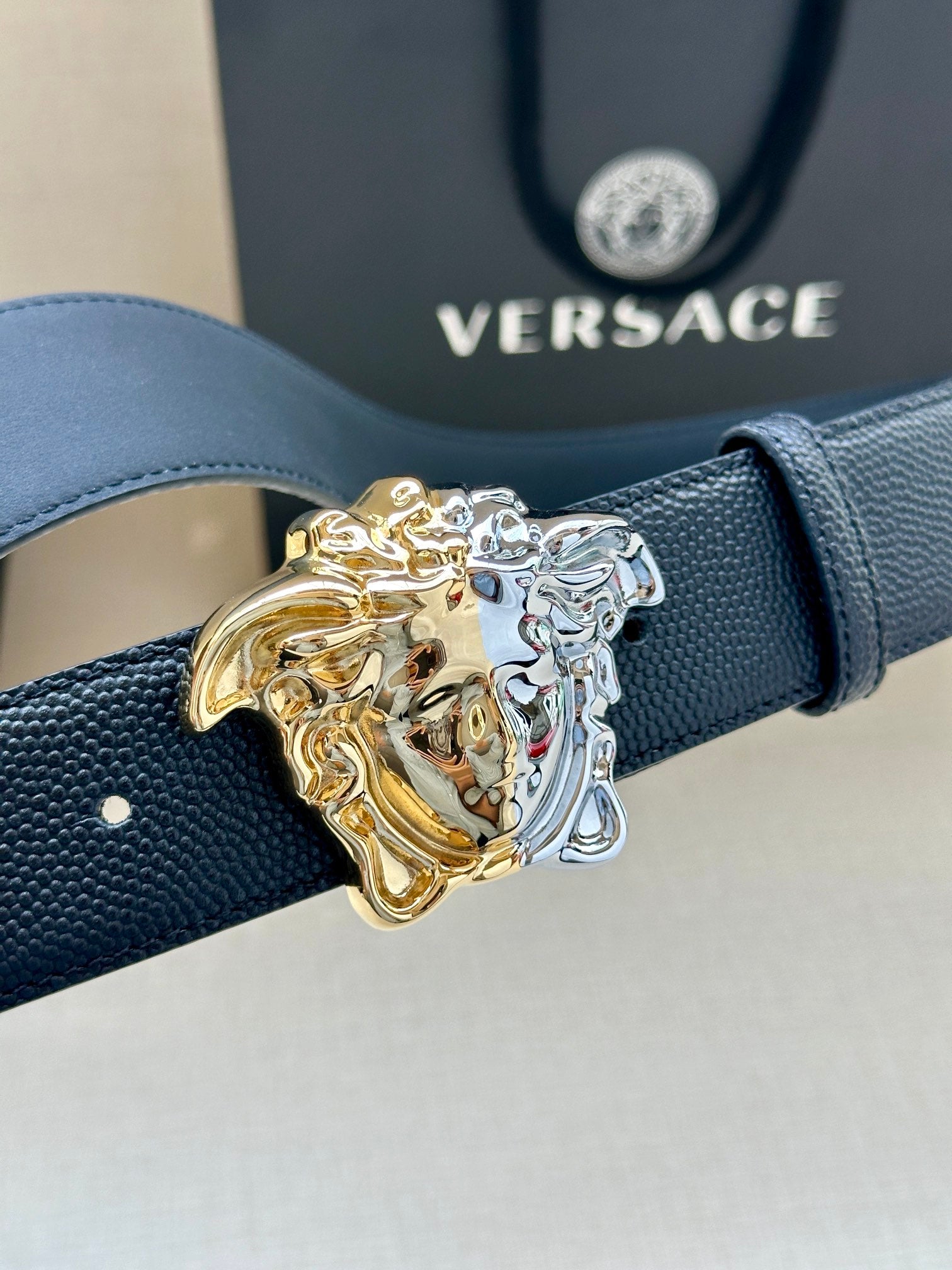 Versace blue leather belt buckle close-up with gold and silver Medusa crest
