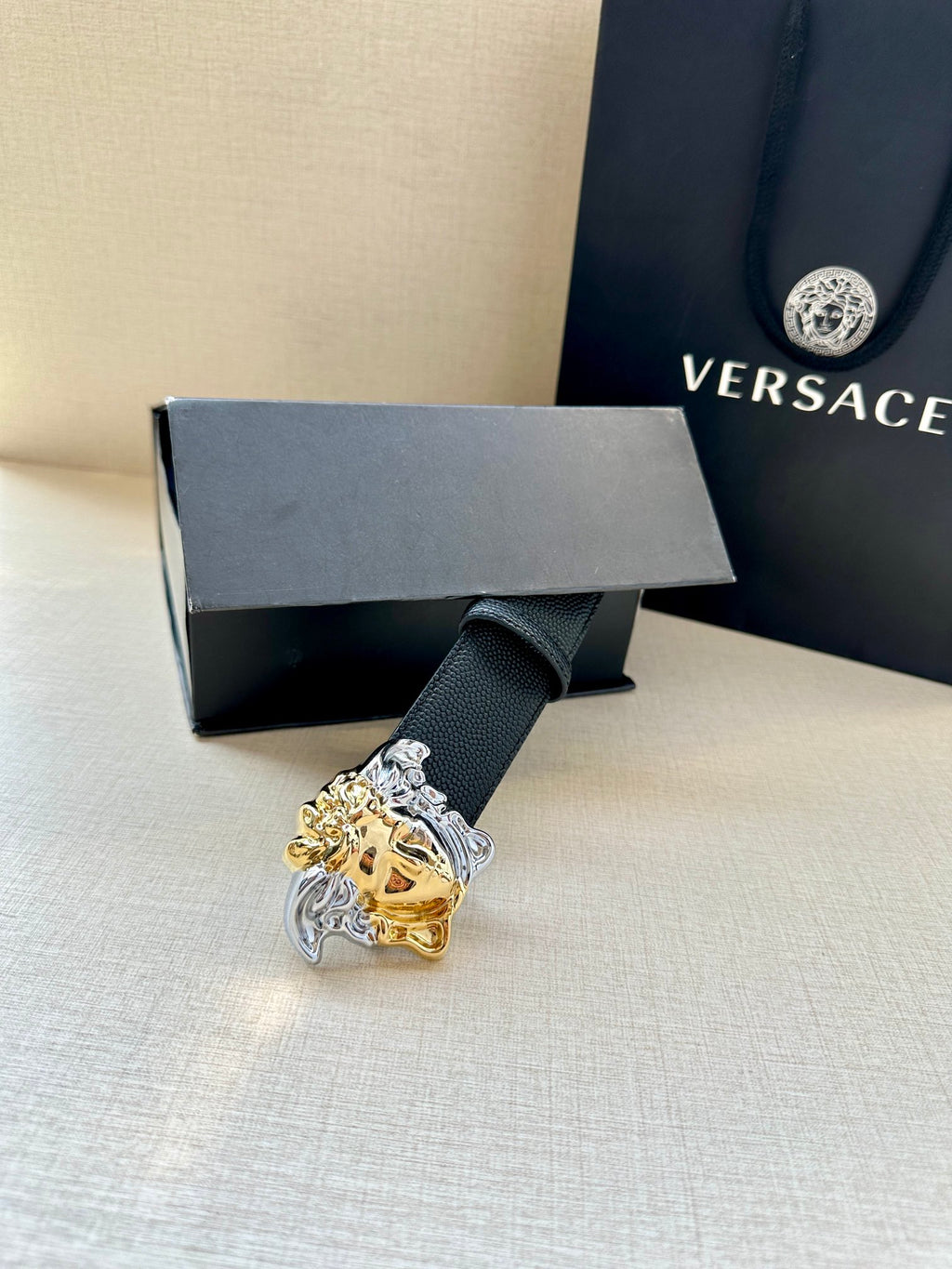 Versace navy belt with Medusa buckle resting on a gift box