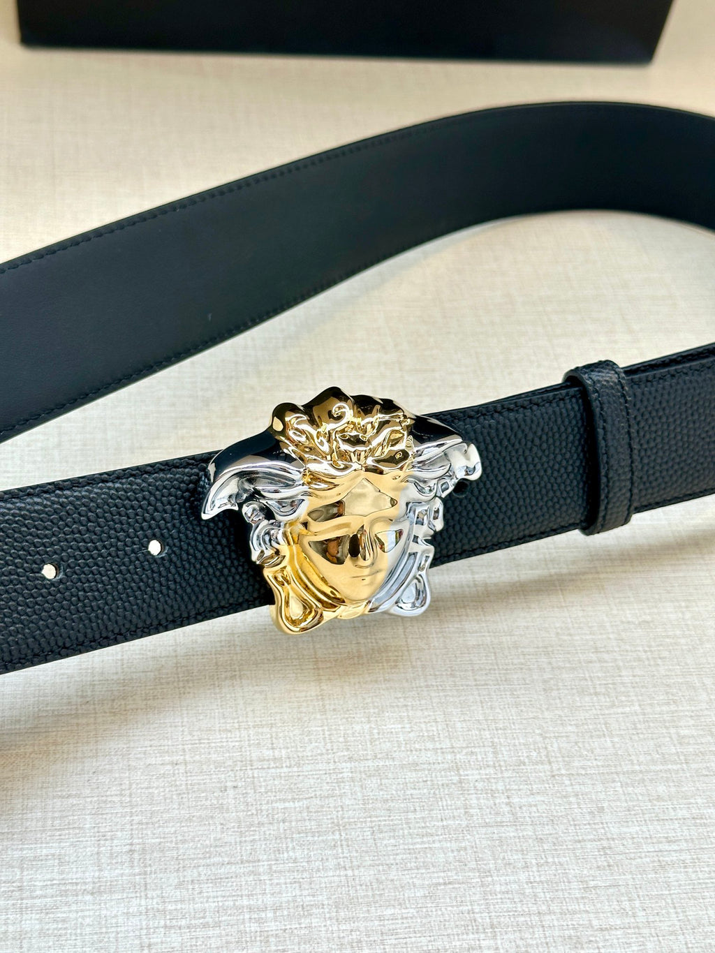 Navy leather belt with textured strap and ornate gold/silver Medusa buckle detail