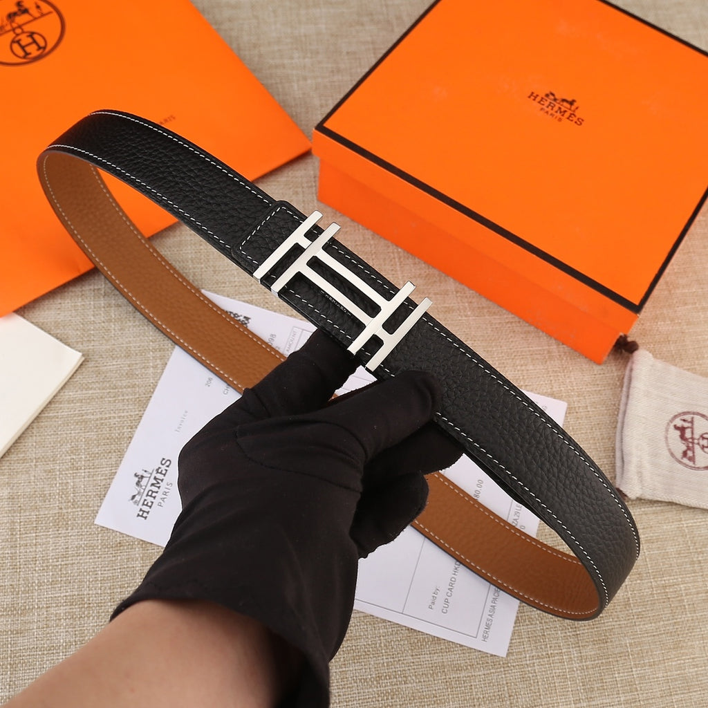 Black leather belt with gold-tone H buckle and contrast white stitching, laid flat