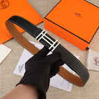 Black leather belt with gold-tone H buckle and contrast white stitching, laid flat