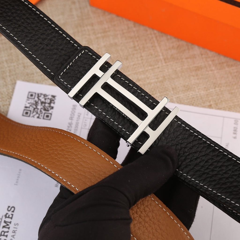 Black leather belt buckle detail with gold-tone H hardware and contrast stitching