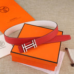 Red leather belt with gold H buckle, laid across a white inner strap.