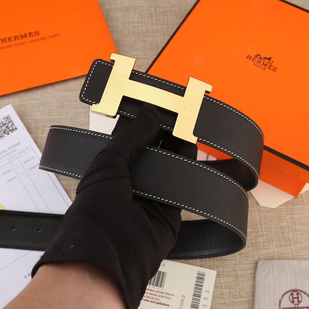 Black leather belt with large gold H buckle and white double-row stitching
