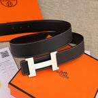 Black leather belt with gold H buckle, perforated strap holes, and white stitching
