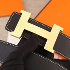 Black leather belt close-up with gold H buckle and white edge stitching