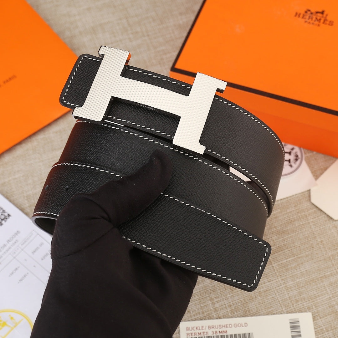 Black leather belt detail showing gold H buckle, textured leather, and white seams
