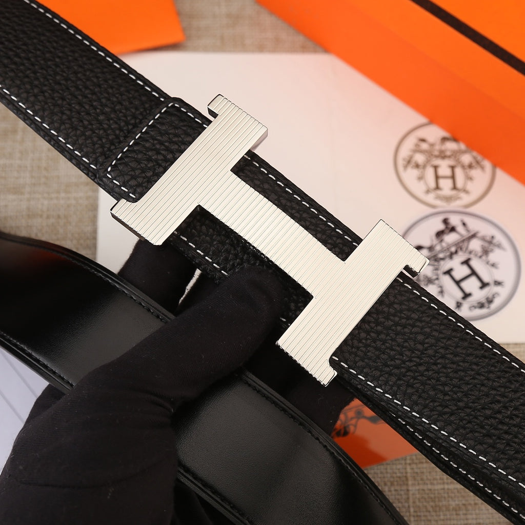 Hermes belt close-up: black textured strap with white stitching and gold H buckle