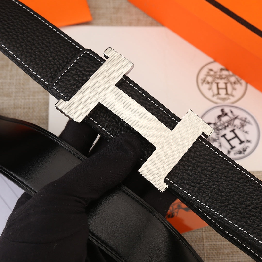 Hermes belt close-up: black textured strap with white stitching and gold H buckle