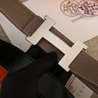Hermes belt buckle close-up with silver-tone H on brown leather strap