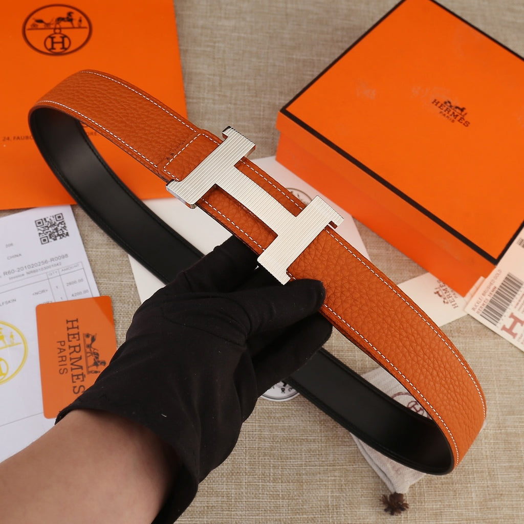 Hermes leather belt with orange textured strap and silver-toned H buckle.