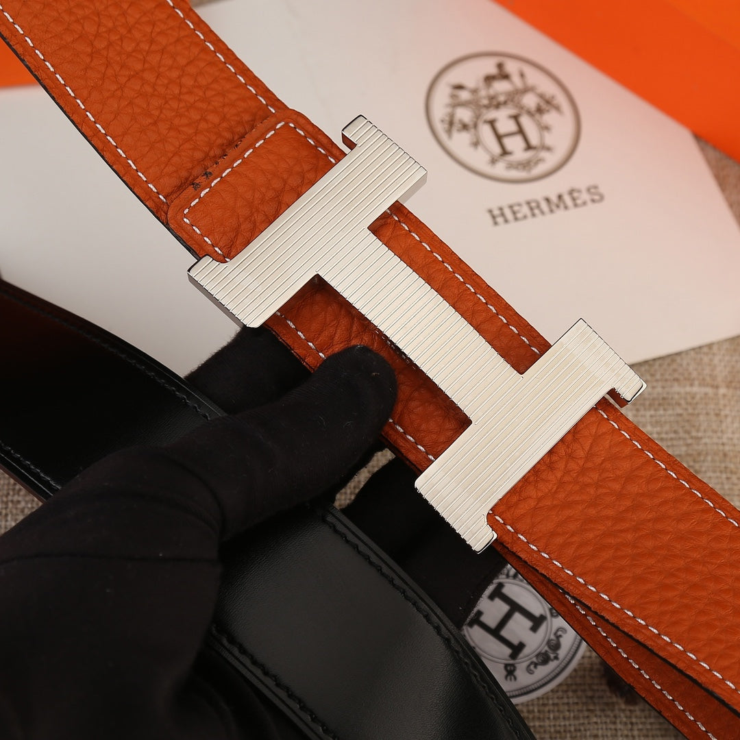 Hermes belt close-up: orange textured strap with silver-toned H buckle.