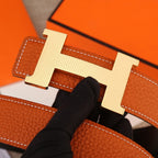 Hermes belt close-up of orange textured strap and silver-toned H buckle.