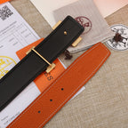 Hermes leather belt with orange strap, hole adjuster, and black end tab.
