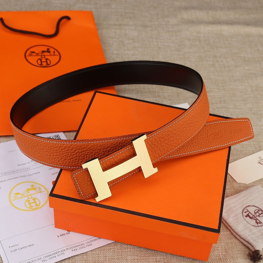 Hermes leather belt with orange textured strap and silver-toned H buckle.