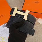 Hermes black leather belt with light gold H buckle and white-stitched strap edge.