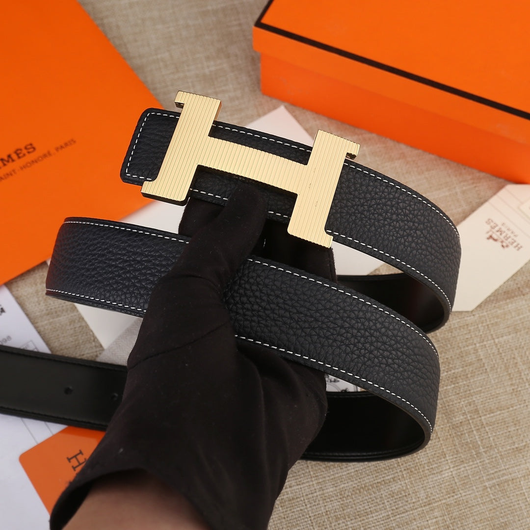 Hermes belt with black leather strap, light gold H buckle, and visible stitch lines.