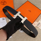 Hermes belt in dark black leather with light gold H-style buckle and stitched edges.