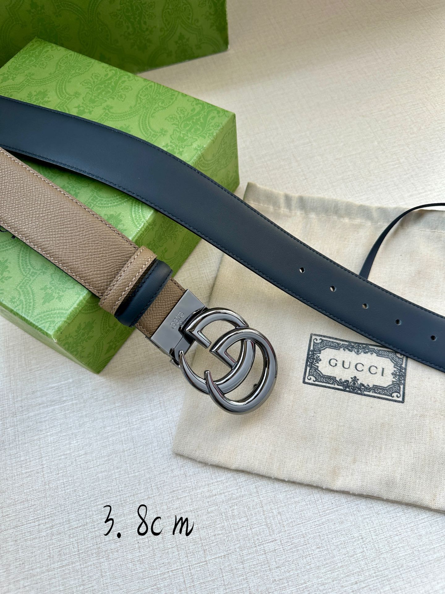 Gucci belt with beige strap, dark blue keeper, silver double-G buckle, and branded tag
