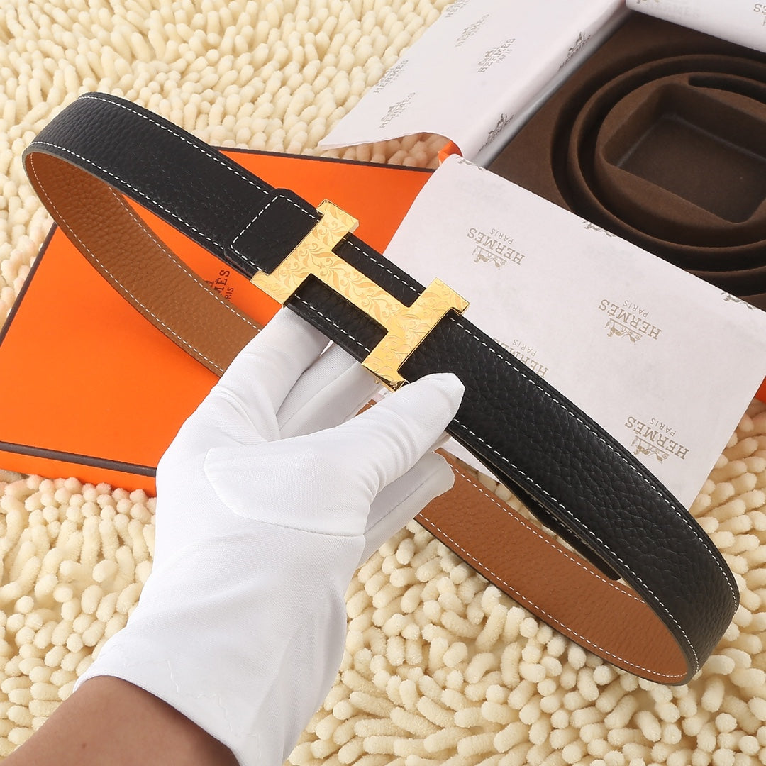 Black leather belt with gold-tone buckle and tan underside, stitched edges and keeper tab