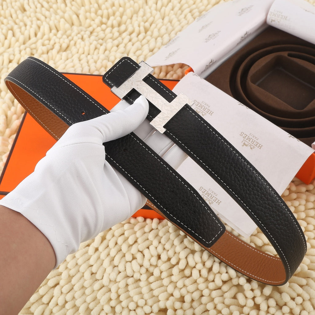 Black leather belt with large gold-tone H buckle, contrast stitching, and tan keeper strap