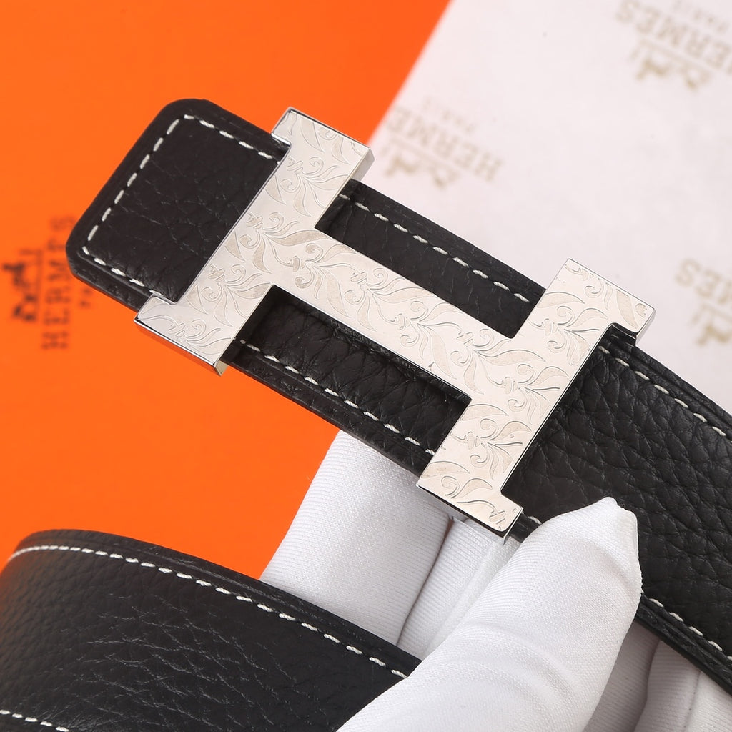 Black leather belt with silver-toned buckle, ornate texture, and white contrast stitching
